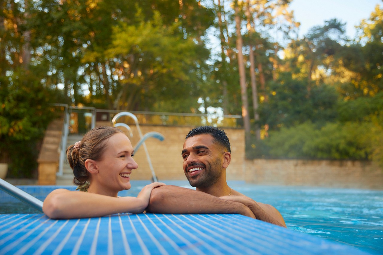 Couple soaking in an outdoor pool surrounded by the forest.